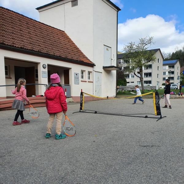 Kinder spielen Tennis auf dem Pausenhof
