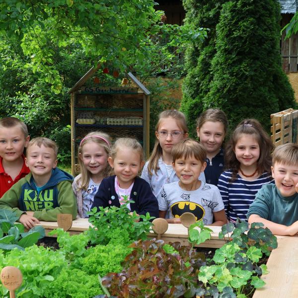 Stolze Kinder am Hochbeet mit Salat