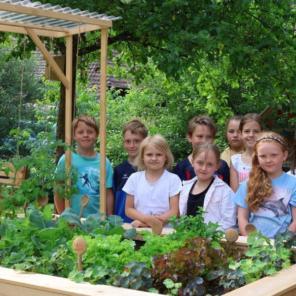 Stolze Kinder am Hochbeet mit Salat